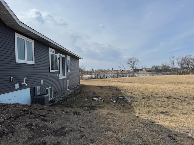 view of yard with central air condition unit and a water view