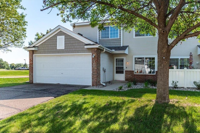 view of front facade with a front yard, fence, concrete driveway, a garage, and brick siding