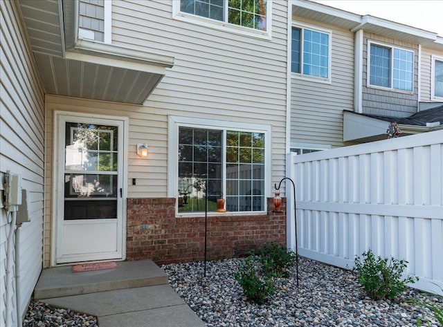 property entrance featuring brick siding and fence