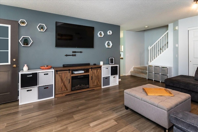 living area featuring stairway, a textured ceiling, and dark wood finished floors