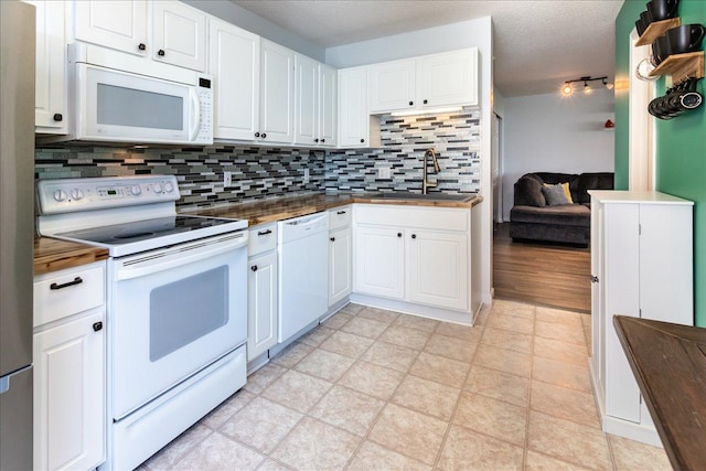 kitchen with a sink, white appliances, tasteful backsplash, and white cabinetry