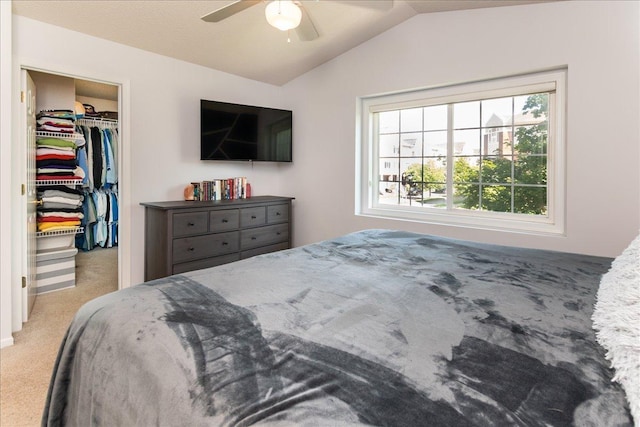 carpeted bedroom with a closet, a walk in closet, ceiling fan, and vaulted ceiling