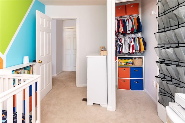 bedroom with light carpet, baseboards, and a closet