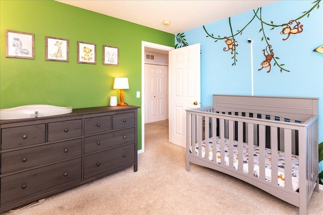 carpeted bedroom featuring a nursery area, visible vents, and a textured ceiling