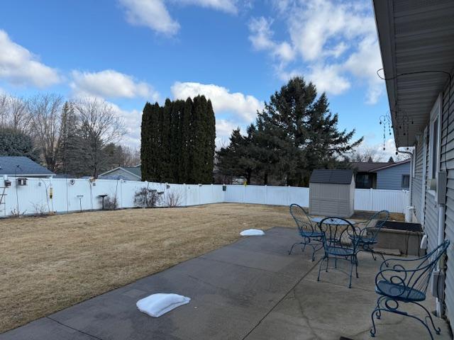 view of patio featuring outdoor dining space, an outdoor structure, a storage unit, and a fenced backyard