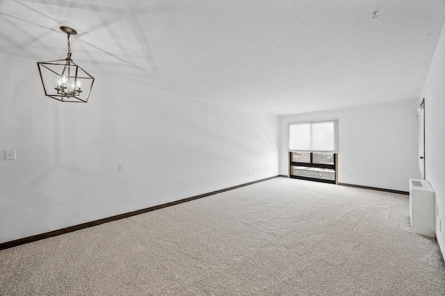 carpeted spare room featuring an inviting chandelier, baseboards, and a textured ceiling