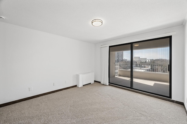 carpeted empty room featuring a city view, radiator, a textured ceiling, and baseboards