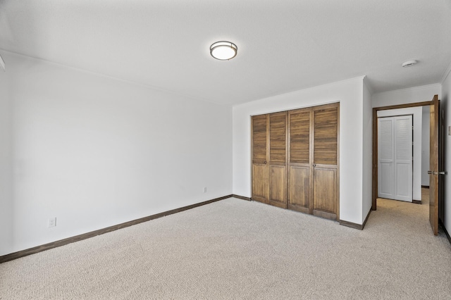 unfurnished bedroom featuring light carpet, baseboards, and a closet