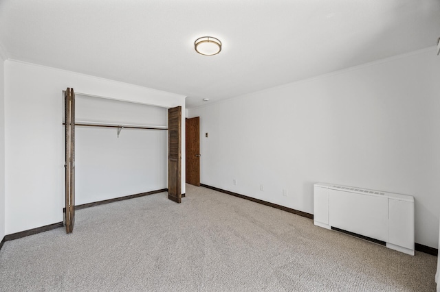 unfurnished bedroom with crown molding, baseboards, radiator heating unit, and carpet