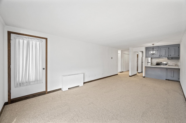 unfurnished living room featuring light carpet, radiator, baseboards, and a chandelier