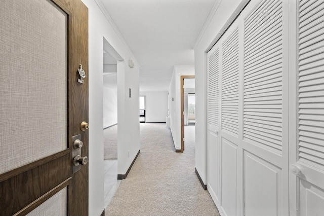 hall featuring baseboards, light colored carpet, and ornamental molding