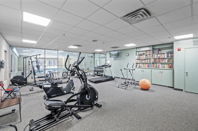 workout area featuring a paneled ceiling, visible vents, and baseboards