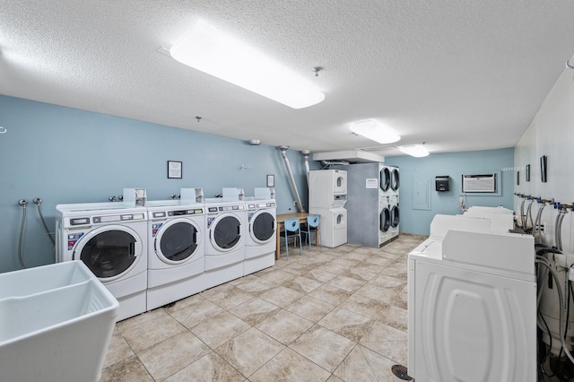 community laundry room with a sink, stacked washer and dryer, washing machine and dryer, and a textured ceiling