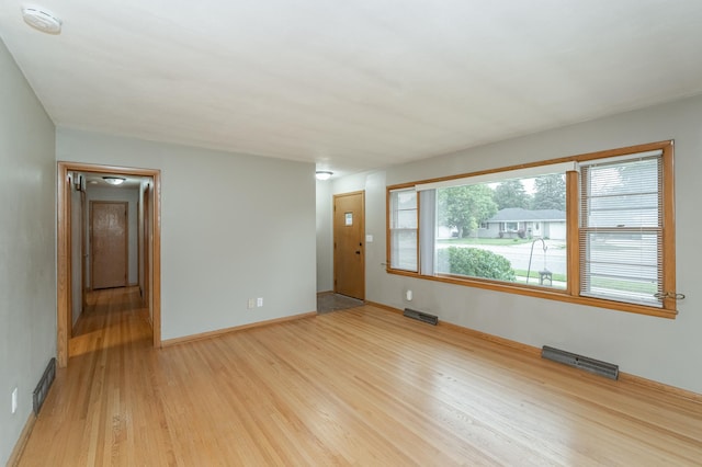 empty room featuring baseboards, visible vents, and light wood-type flooring