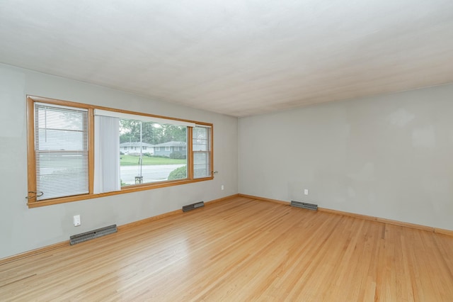 spare room featuring visible vents, baseboards, and wood finished floors