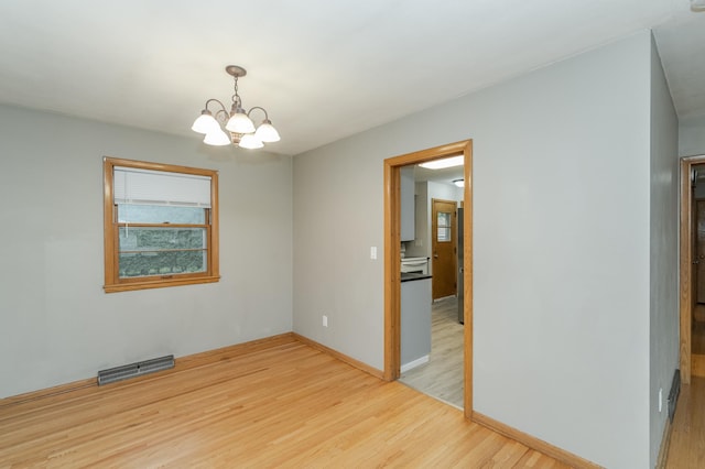 unfurnished room with visible vents, baseboards, an inviting chandelier, and light wood-style flooring