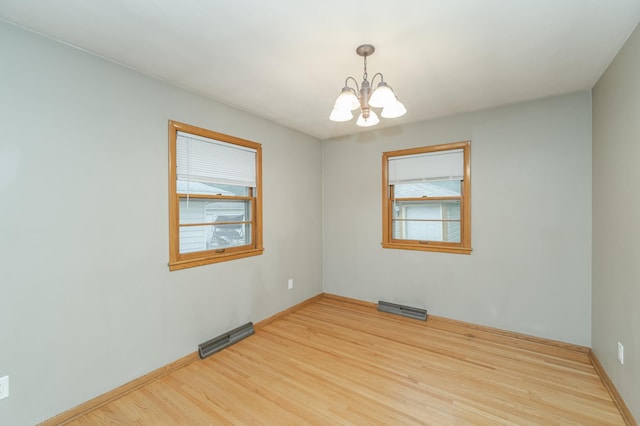 unfurnished room with visible vents, a healthy amount of sunlight, and wood finished floors