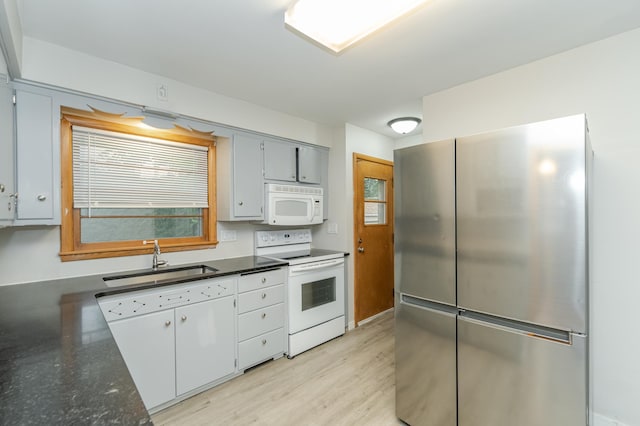 kitchen featuring white appliances, light wood finished floors, and a sink