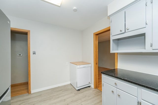 kitchen featuring dark stone countertops, baseboards, open shelves, refrigerator, and light wood-style flooring