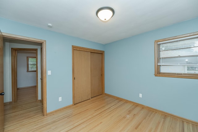 unfurnished bedroom featuring a closet, baseboards, and light wood-style floors