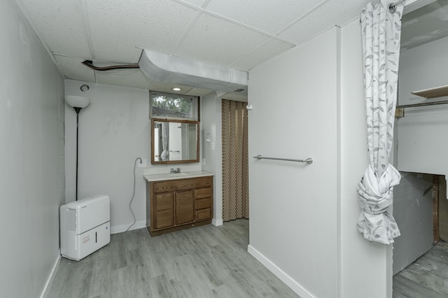 bathroom featuring a drop ceiling, baseboards, wood finished floors, and vanity