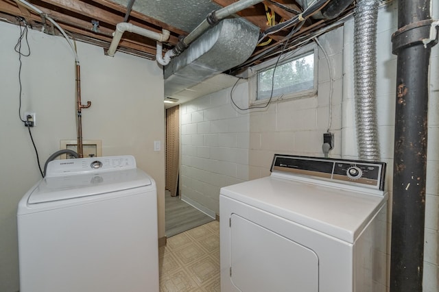 clothes washing area with washing machine and clothes dryer, laundry area, and light floors