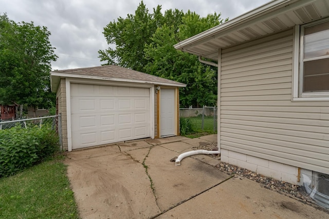 detached garage featuring fence and driveway