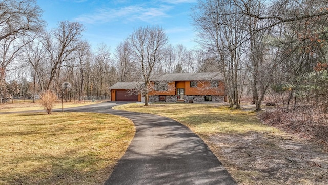 view of front of house featuring aphalt driveway, stone siding, a front lawn, and a garage