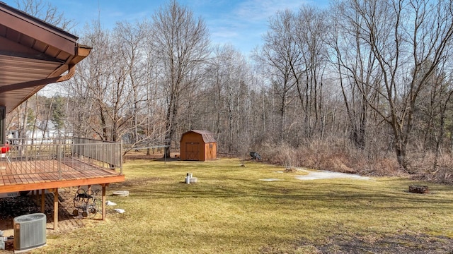 view of yard featuring a forest view, cooling unit, a deck, an outbuilding, and a storage unit