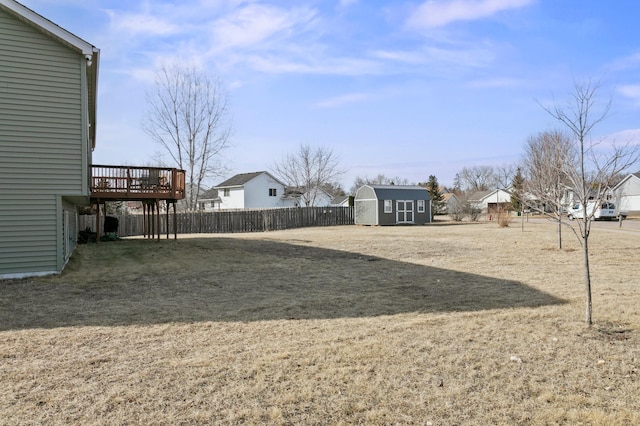 view of yard featuring a deck, a storage shed, an outdoor structure, and fence