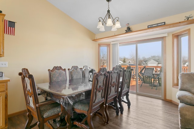 dining area featuring an inviting chandelier, lofted ceiling, wood finished floors, and baseboards