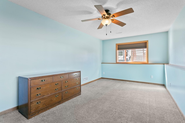 unfurnished room featuring visible vents, baseboards, carpet floors, a textured ceiling, and a ceiling fan