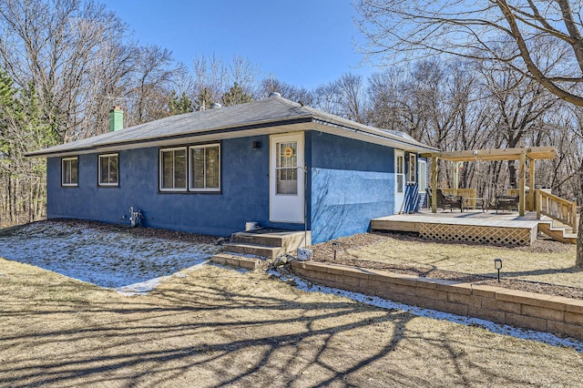 view of front of property with stucco siding, a chimney, a shingled roof, and a deck