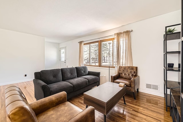 living area with baseboards, visible vents, and wood finished floors