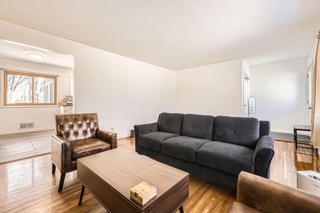 living room featuring baseboards, visible vents, and hardwood / wood-style flooring