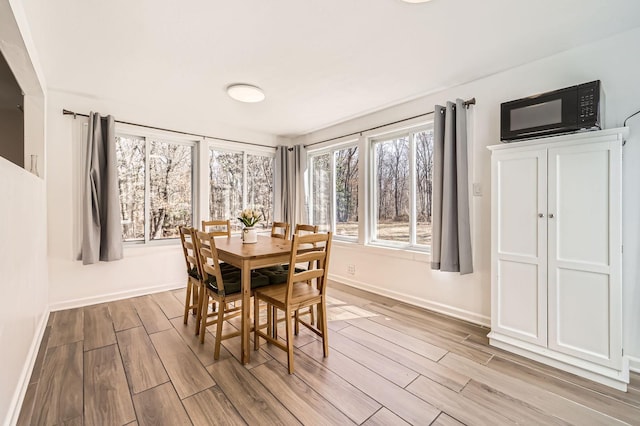 dining area with baseboards and light wood-style flooring