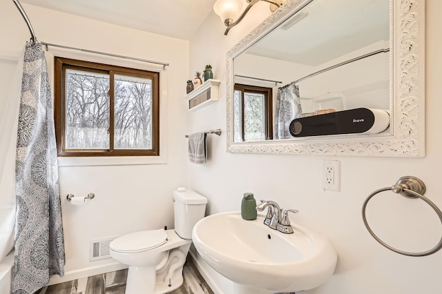 full bathroom featuring toilet, a sink, a shower with curtain, wood finished floors, and visible vents