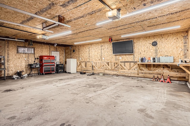garage featuring a workshop area, a garage door opener, and freestanding refrigerator