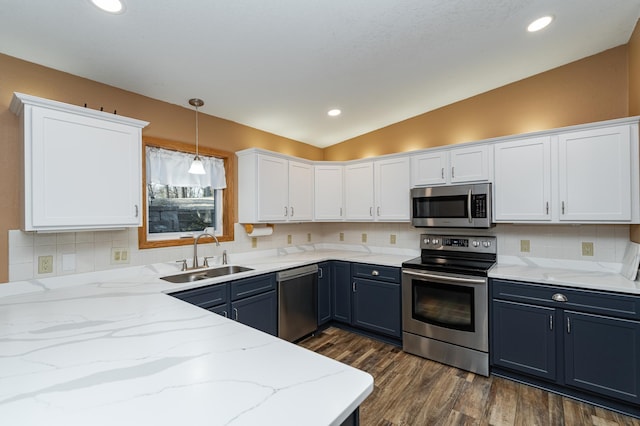 kitchen featuring a sink, dark wood finished floors, appliances with stainless steel finishes, white cabinets, and vaulted ceiling