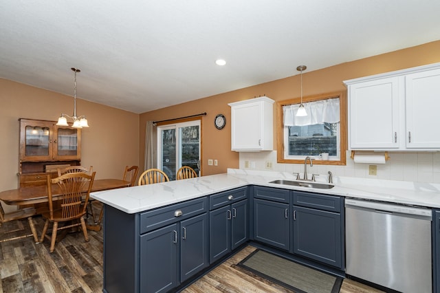 kitchen with dishwasher, a peninsula, wood finished floors, white cabinetry, and a sink