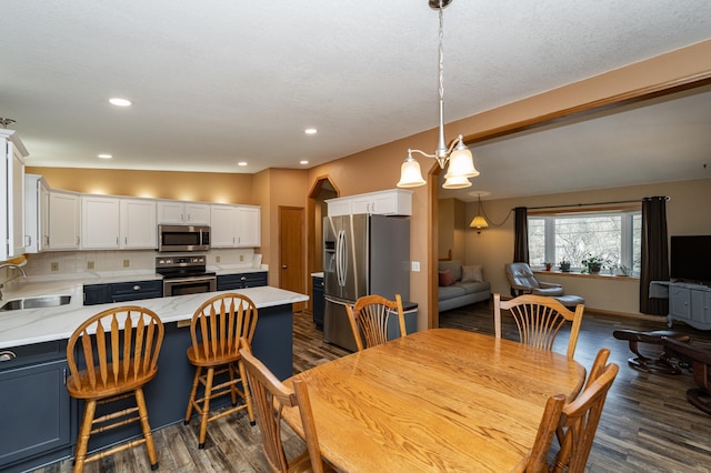 dining room with dark wood finished floors, recessed lighting, and baseboards