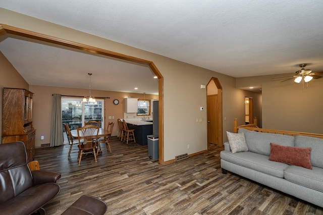 living room featuring visible vents, arched walkways, baseboards, ceiling fan, and dark wood-style flooring