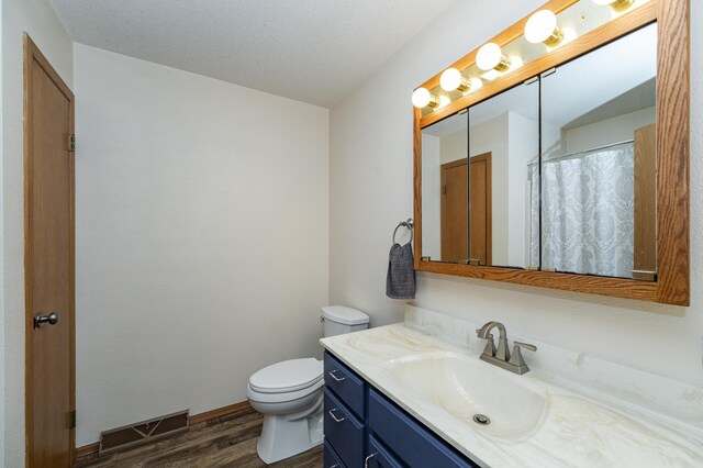 bathroom with vanity, wood finished floors, visible vents, baseboards, and toilet