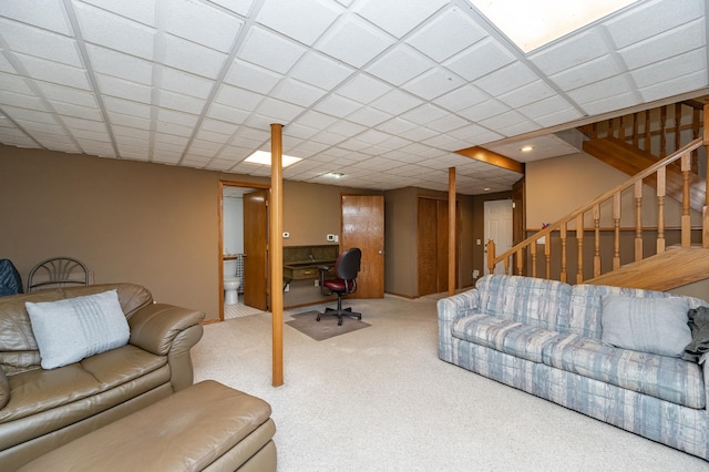 carpeted living area with stairs and a drop ceiling