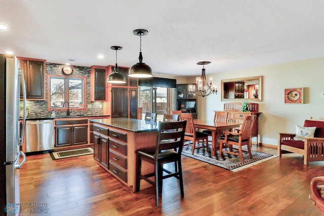 kitchen with stainless steel appliances, dark wood-type flooring, an inviting chandelier, and decorative backsplash