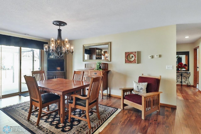 dining space featuring baseboards, wood-type flooring, and a chandelier