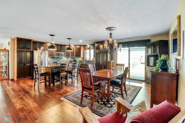 dining area with a textured ceiling, wood finished floors, and a chandelier