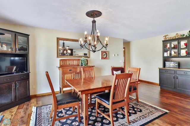 dining area with baseboards, an inviting chandelier, and light wood finished floors