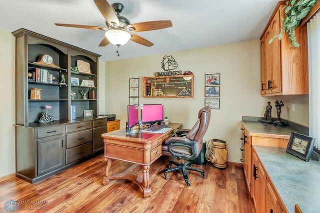 home office with light wood-style flooring, baseboards, and a ceiling fan