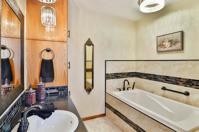 full bath featuring baseboards, an inviting chandelier, a sink, tile patterned floors, and a bath